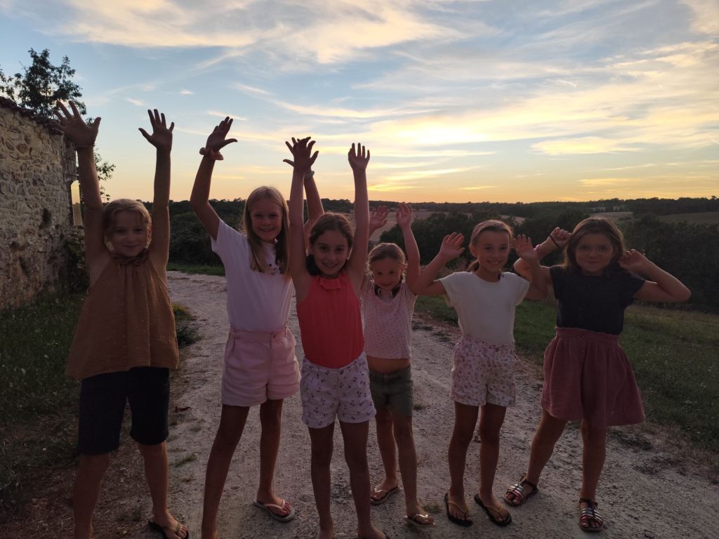 Jeunes filles du camp spirituel, bras levés au coucher du soleil