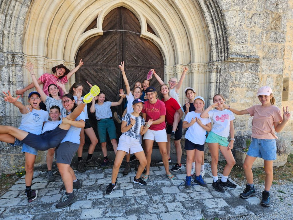 Groupe de jeunes filles du camp spirituel devant le portail d'une église